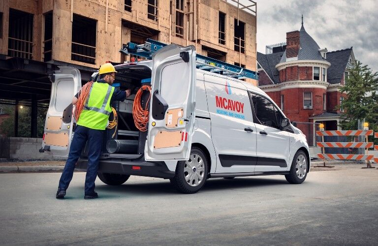 Rear passenger angle of a white 2020 Ford Transit Connect with an employee getting equipment out of the back