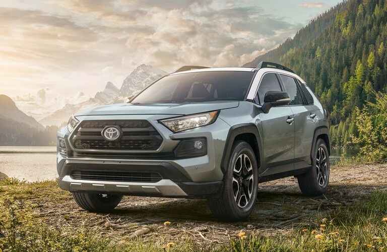 Front driver angle of a light blue 2020 Toyota RAV4 parked by a lake