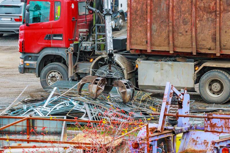 A grapple truck grabbing construction site trash