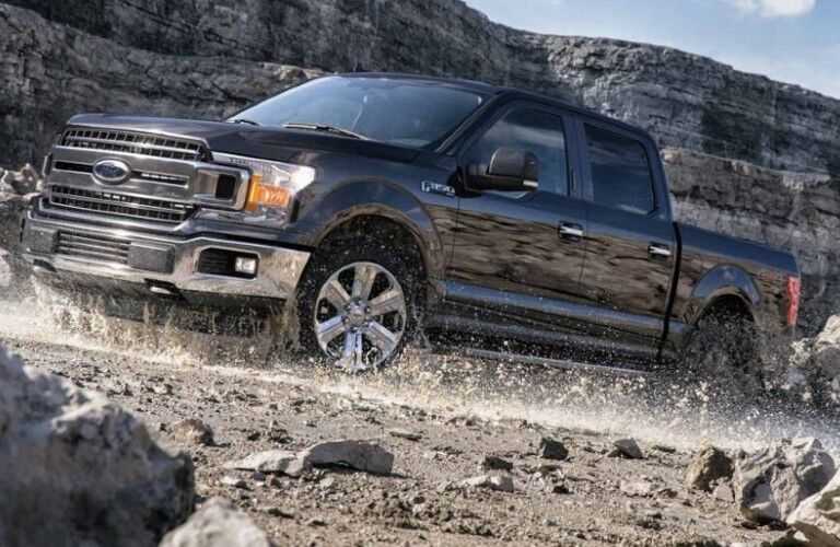 Side view of 2020 Ford F-150 XLT driving on gravel road