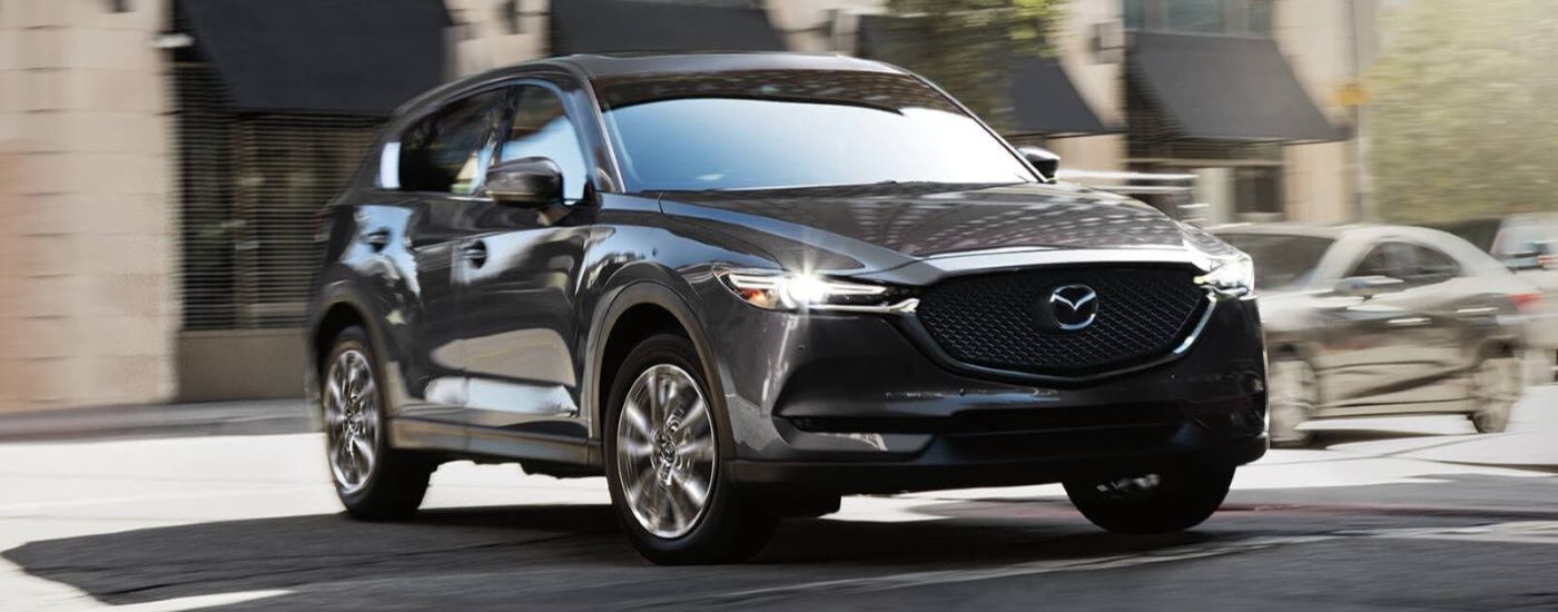 Black 2021 Mazda CX-5 driving through a city intersection