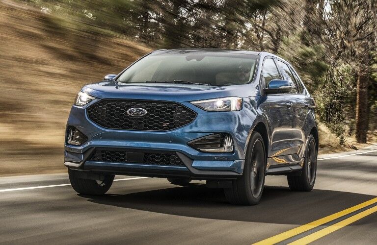 Front driver angle of a blue 2020 Ford Edge driving down a road