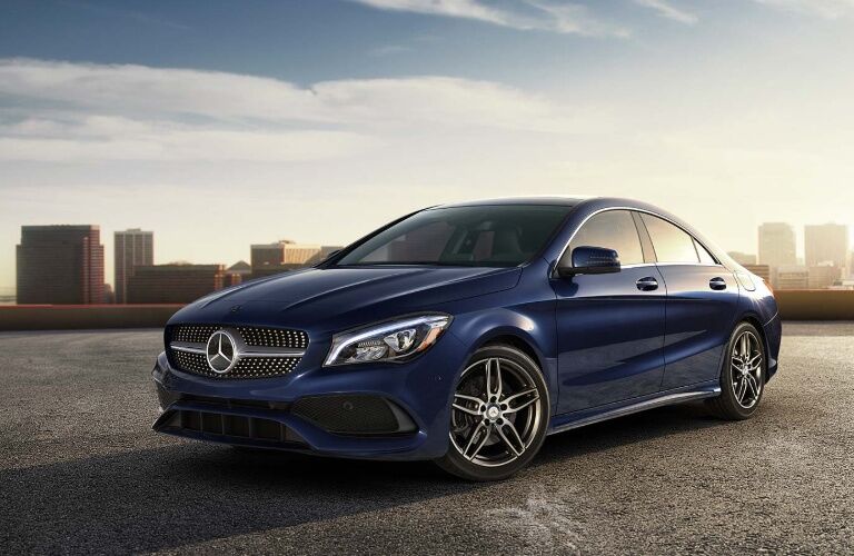 blue mercedes-benz cla coupe with skyscrapers in the background