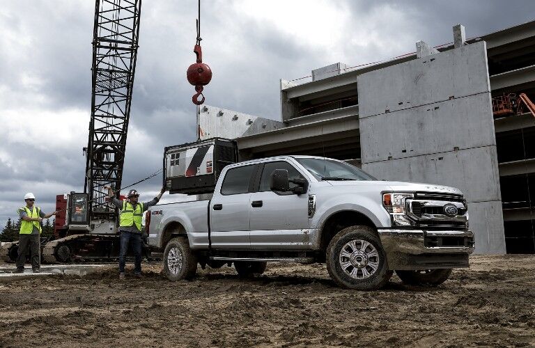 Front passenger angle of a white 2020 Ford Super Duty with workers loading the truck bed