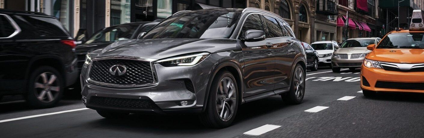 Front driver angle of a grey 2021 INFINITI QX50 driving in a city