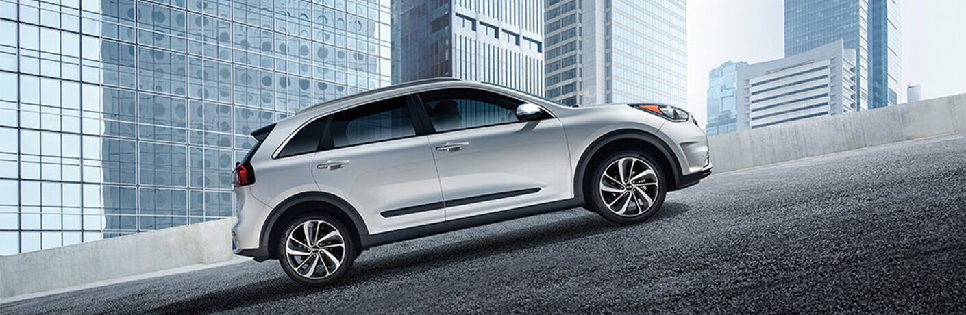 right side view of white kia niro driving up hill