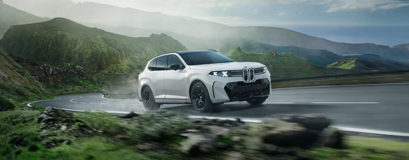 White 2026 BMW X5 driving around a bend.