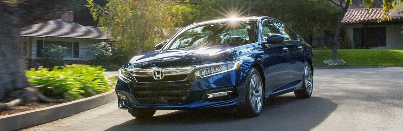 Front driver angle of a blue 2020 Honda Accord Hybrid driving through a neighborhood