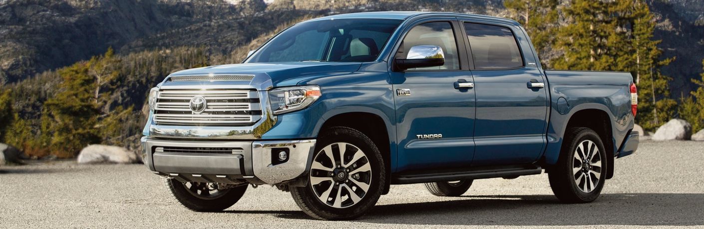 Front driver angle of a blue 2020 Toyota Tundra parked in front of a mountain