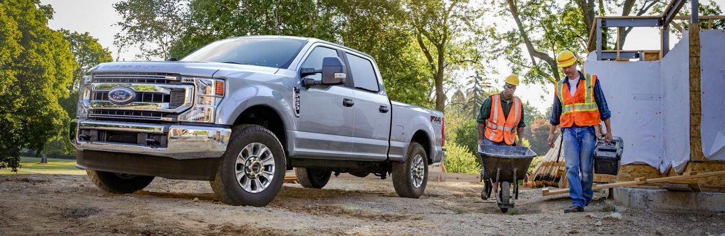 Front driver angle of a silver 2020 Ford Super Duty with construction workers nearby