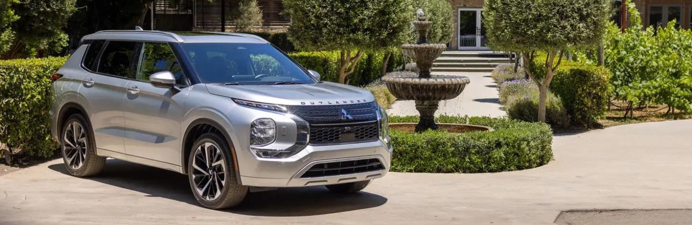 2024 Mitsubishi Outlander parked near a garden in front of a house