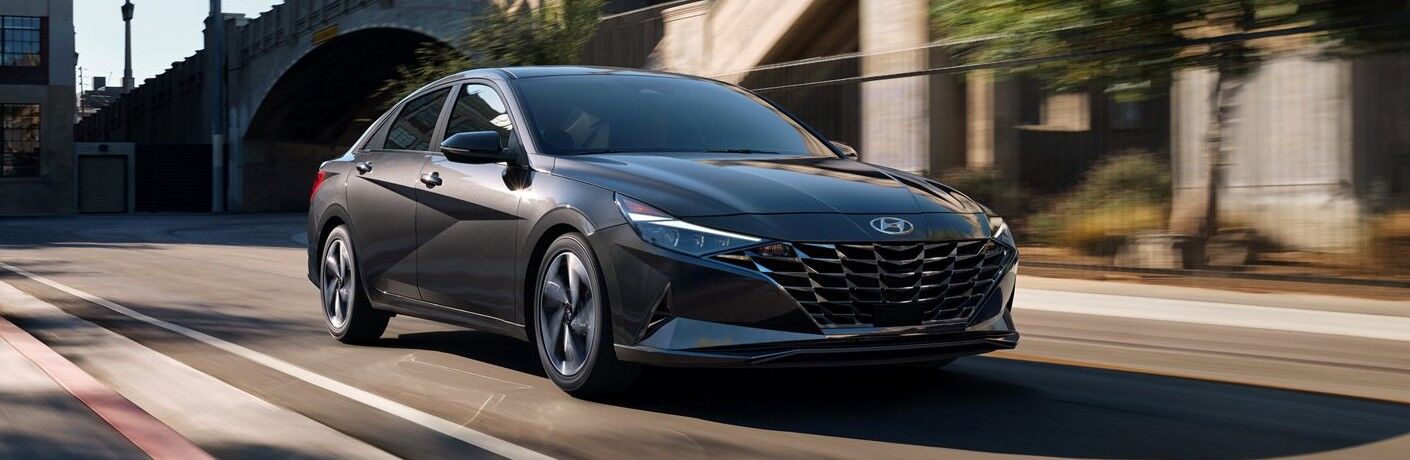 Front passenger angle of a black 2021 Hyundai Elantra driving in a city