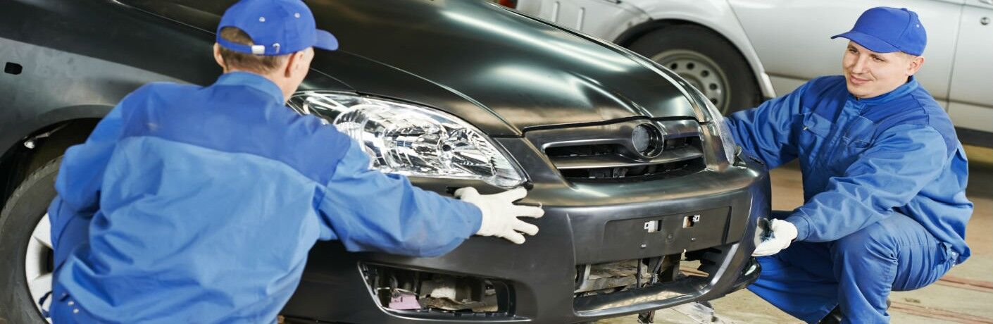 Damaged vehicle being fixed by two workers
