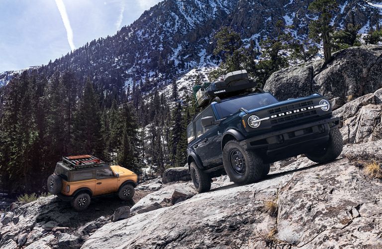 A blue 2021 Ford Bronco and orange 2021 Ford Bronco parked on a mountain