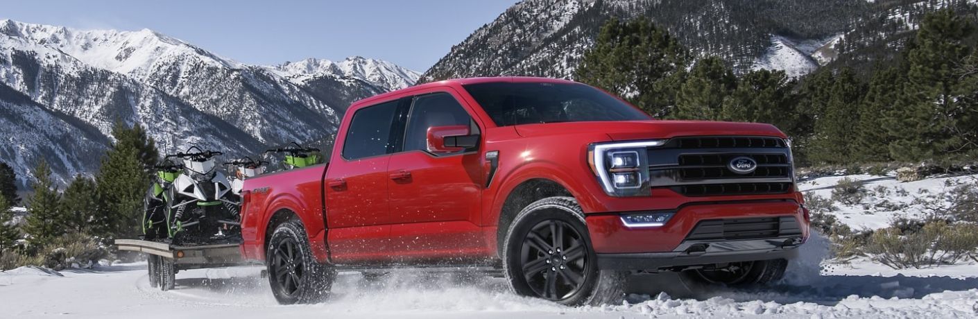 One red color 2022 Ford F-150 is running on a snow-laden road.