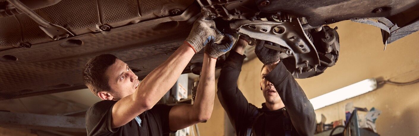 Mechanics repairing a transmission in a car