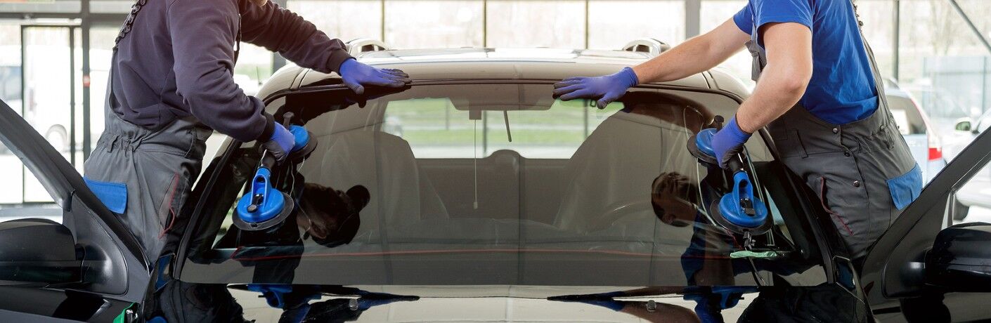 Mechanics replacing the windshield on a car