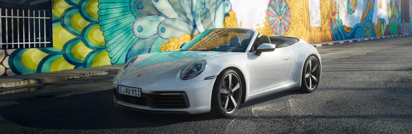 a Porsche car parked near a wall painted with pictures