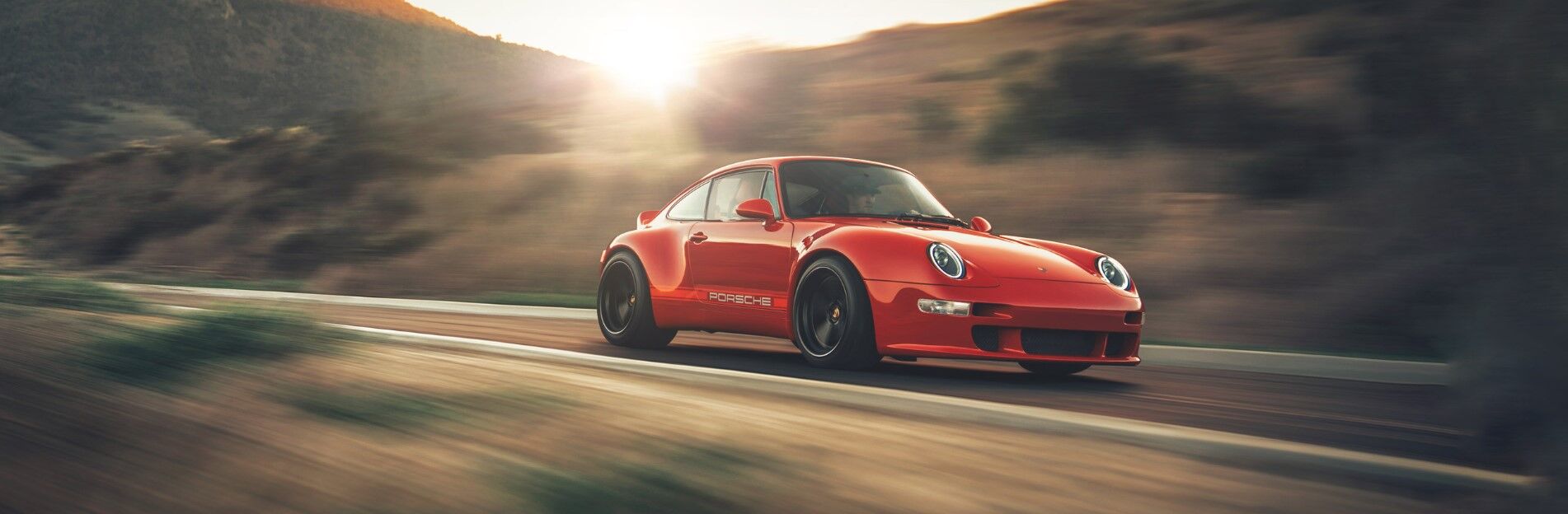 a red Porsche Coupe model driving fast on a road