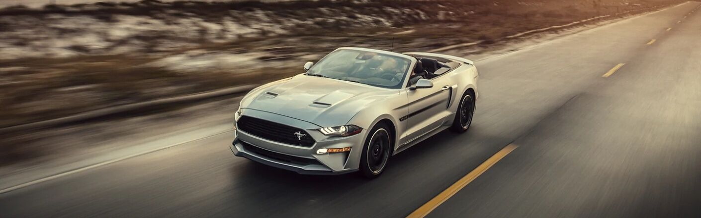 Ford Mustang convertible drives along a highway