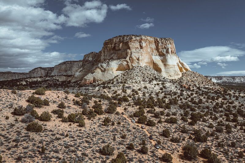 Convoy on a dirt trail below a sandstone butte near Kanab Utah