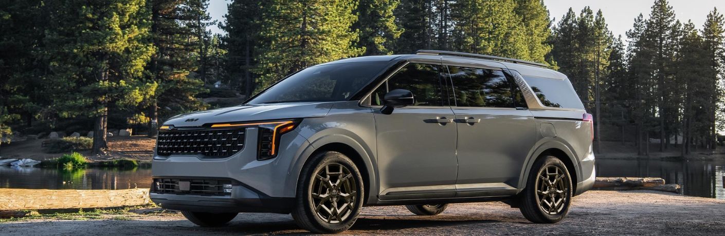 side view image of the 2025 Kia Carnival MPV parked near a lake