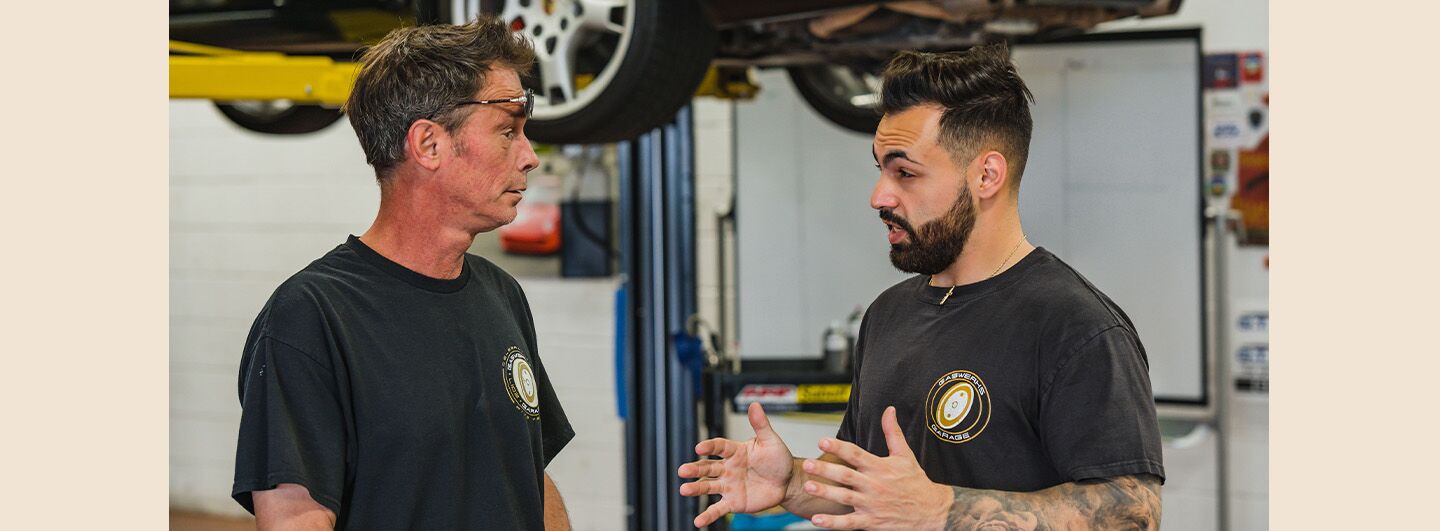 Two men in a car service center garage discussing Gaswerks Garage.