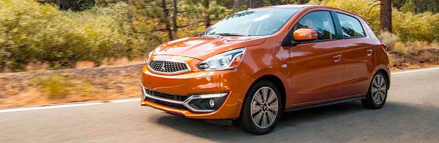 2020 Mitsubishi Mirage orange driving down road past trees