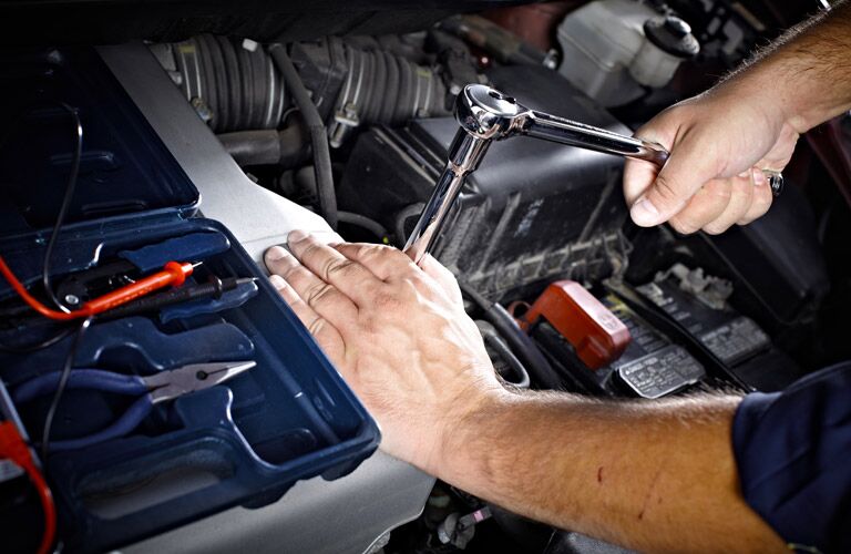 Mechanic using wratchet under car hood