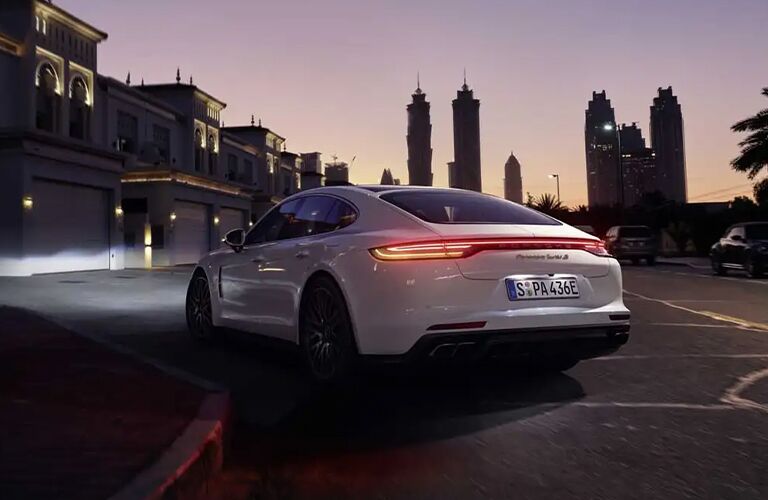 white 2021 Porsche Panamera rear fascia driver side turning on street at night