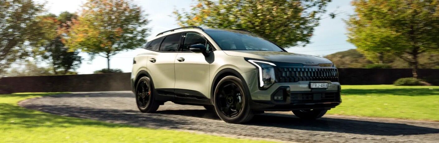 2027 Kia Sportage on a road through a green yard
