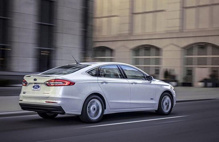 Rear view of white 2019 Ford Fusion driving through city