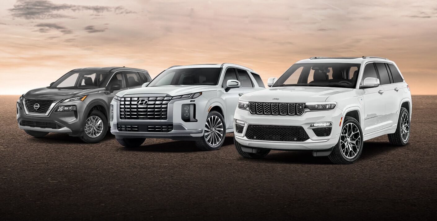 A gray Nissan Rogue, white Hyundai Palisade and white Jeep Cherokee parked in a lot at golden hour.