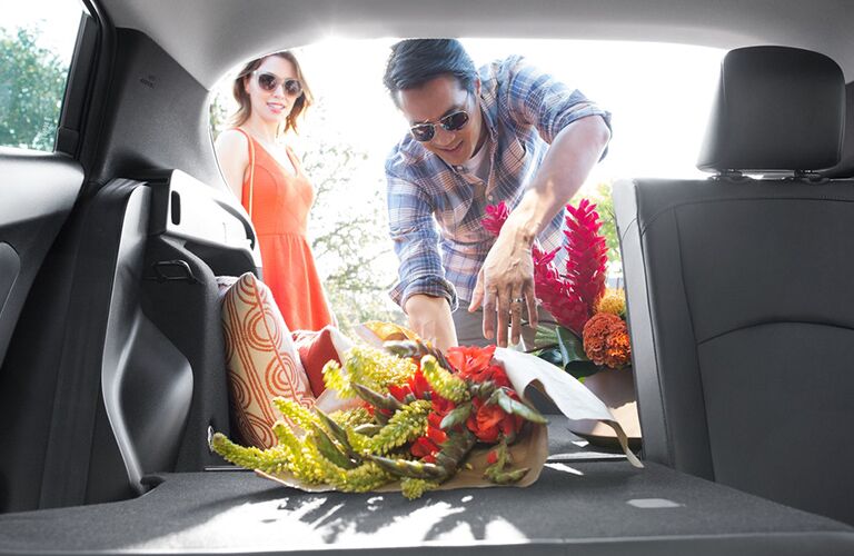 Man reaches for flowers in the rear of a Toyota Prius