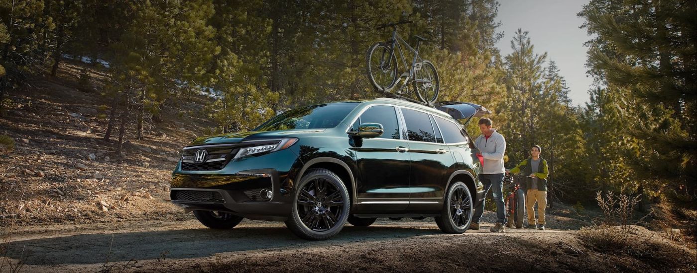 Black 2020 Honda Pilot parked off-road next to a family with bikes