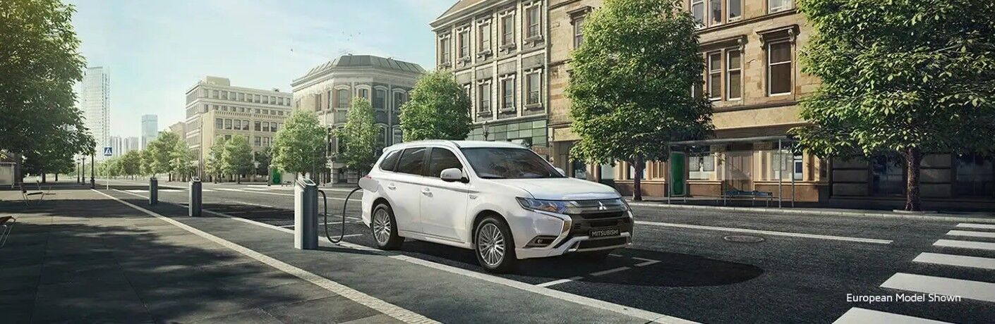 2020 Mitsubishi Outlander PHEV white charging on city street european model shown