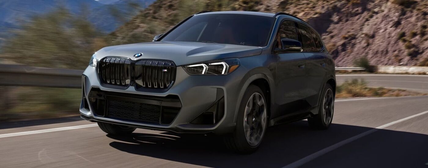 Grey 2026 BMW X1 M35i driving down a road.
