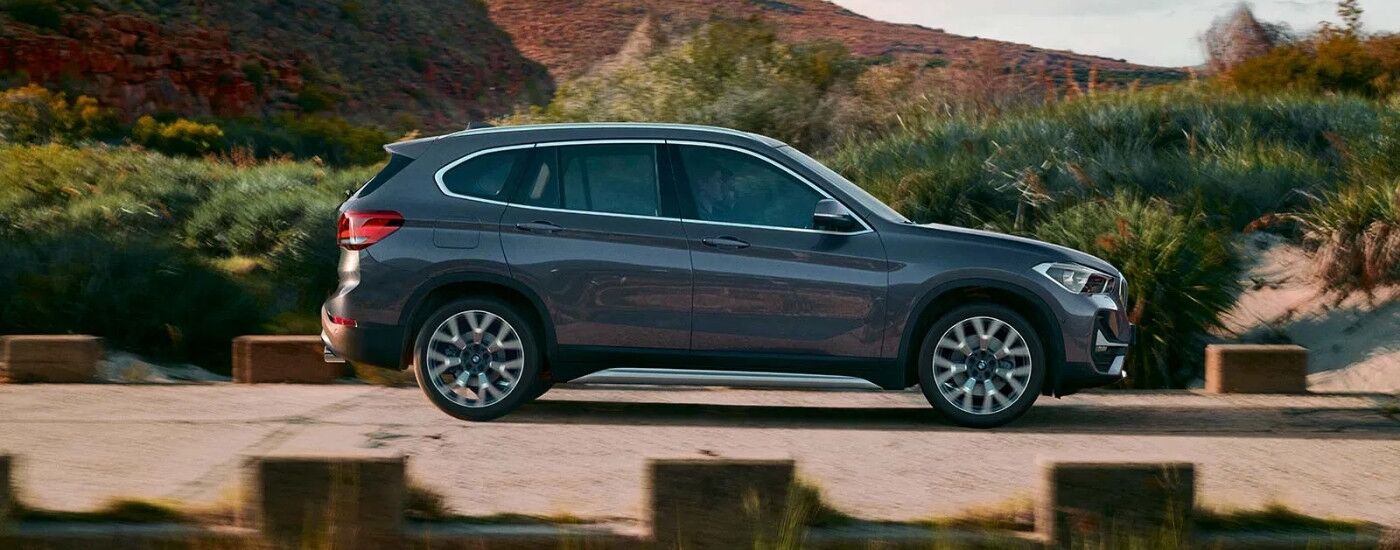 Side view of a green 2020 BMW X1 driving on an open road