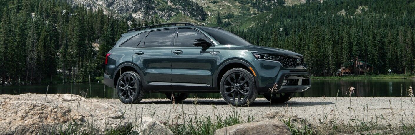 2021 Kia Sorento exterior side shot parked on a gravel field with a background of forest trees and mountains