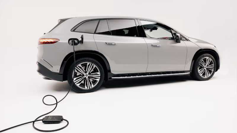 A Mercedes-Benz EV at a home charging station with a long cord