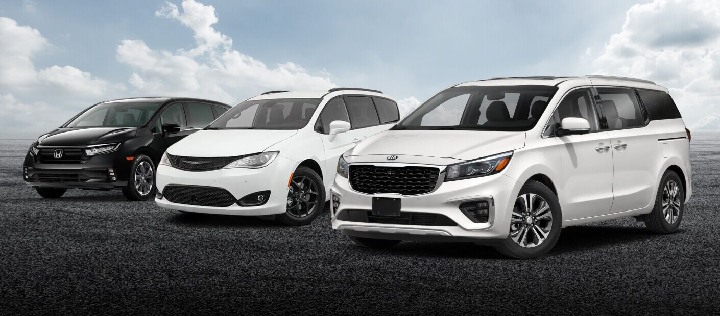 A black Honda Odyssey, white Chrysler PAcifica and white Kia Sedona parked under a cloudy sky.