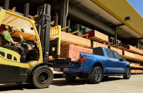 Forklift loading lumber into bed of 2022 Ford F-150 Lightning