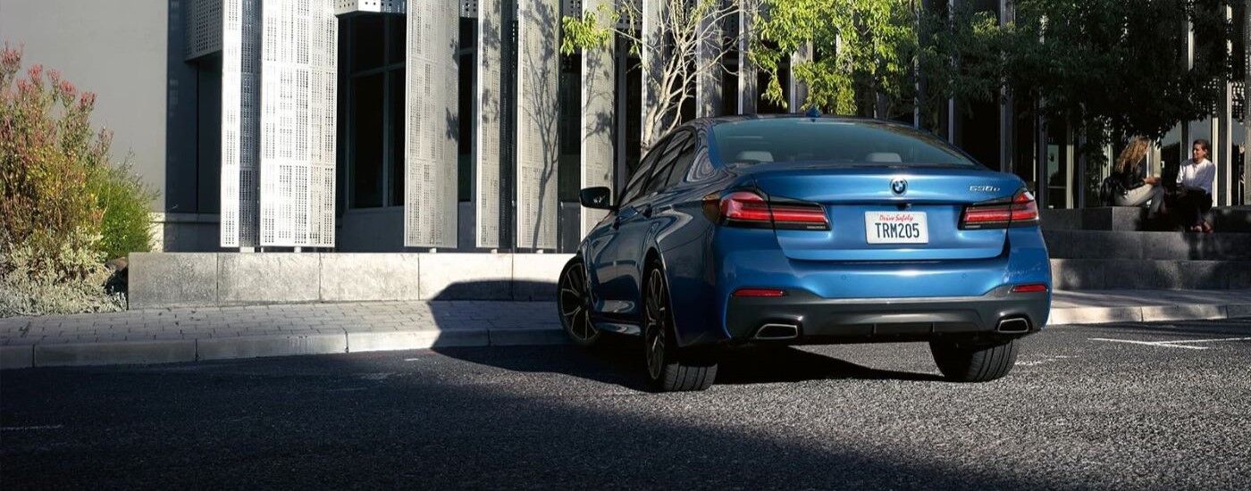 Blue 2023 BMW 5 Series parked outside of a grey building