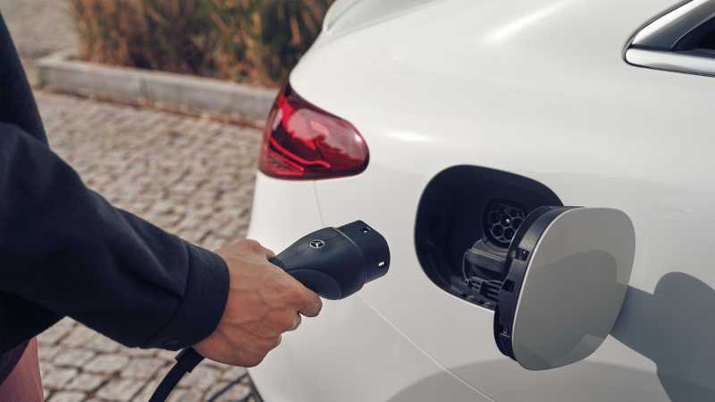 A man about to charge his Mercedes EV at a home, high-speed charging station