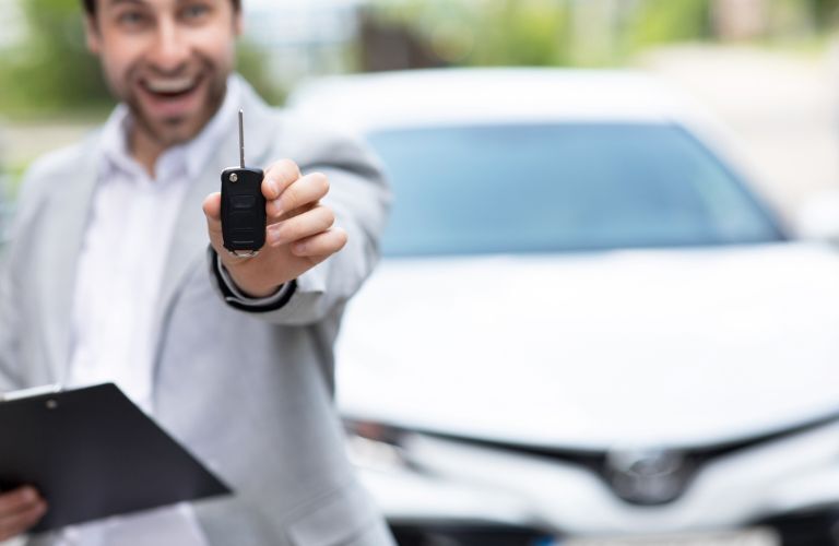 Man showing key as he stands outside his car