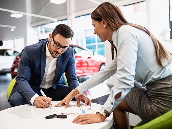 Dealership employee pointing to finance paperwork