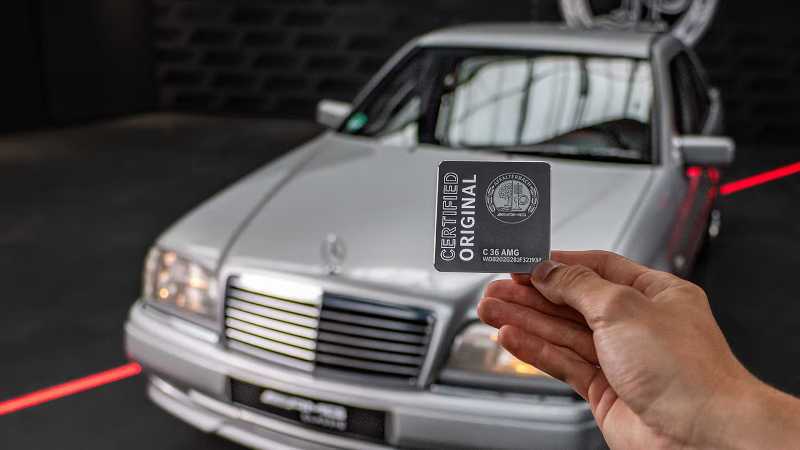 A person holding up their certified original AMG® card in front of their new vehicle