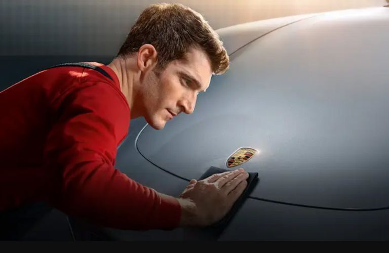a man wiping the hood of a Porsche