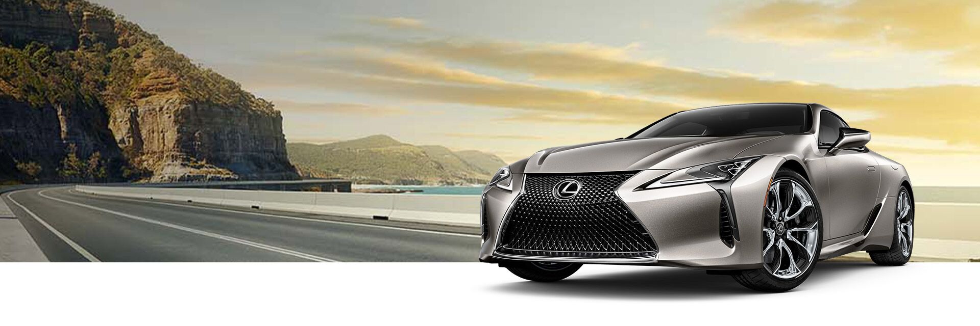 Exterior of the Lexus LC Hybrid shown in Atomic Silver on a coastal highway  background.