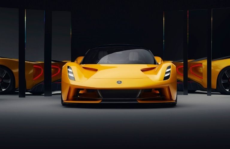 Front view of an orange 2023 Lotus Evija all-electric hypercar parked in a room with mirrors